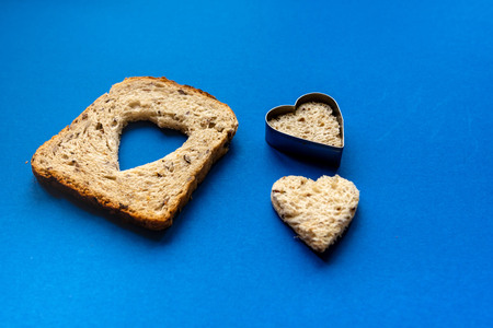 Bread with heart-shaped cut and heart from bread. Wooden Blue Background.の写真素材