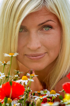 Beautiful, attractive, blonde woman portrait with meadow flowers. Soft focus.の写真素材