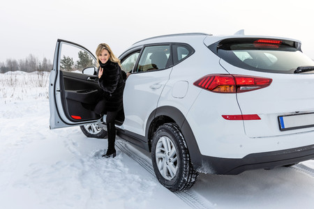The blonde woman gets out of the white suv car and looks back.の写真素材