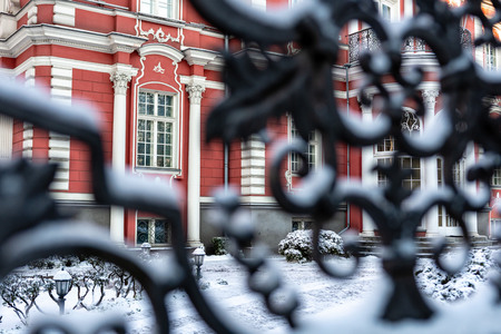 Fragment of the facade of a historic building through snow-covered courtyard gates from metal.の写真素材