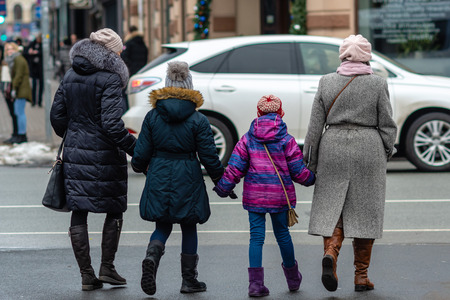 Two women and two children holding hands in cold winter day. Rear viewの写真素材