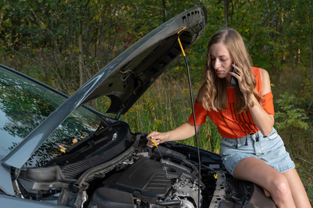 Young woman near broken car speaking by phone needs assistance - Imageの写真素材