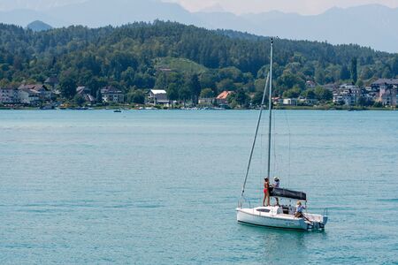 WORTHERSEE, AUSTRIA - AUGUST 08, 2018:  Worthersee view at turquoise water of lake in summer mountains in distance. Tourists enjoying summer vacations.のeditorial素材