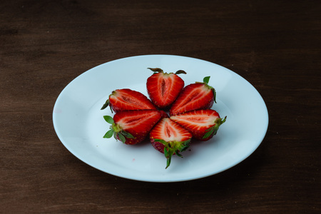 Strawberries on a white plate on a wooden table.の写真素材