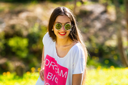 Outdoor portrait of beautiful, emotional, young woman in sunglasses. Soft background. Copy spaceの写真素材