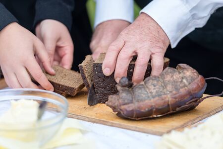 Male hands cutting rye bread on the wooden board, selective focus - Image