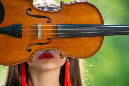 Portrait of a positive young woman. Part of the face is covered by the neck of the violin.の写真素材