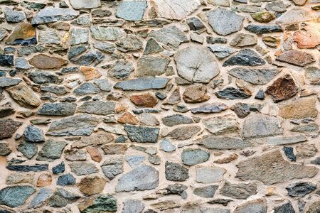 Old, different colors stone wall background texture close up