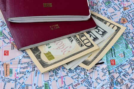 Two passports and a few dollars banknotes on a city map background. Tourism concept.