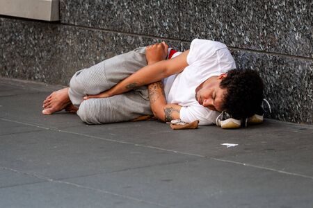 New York, USA - June 23, 2019:  A young man is lying on a pedestrian sidewalk in Manhattanのeditorial素材
