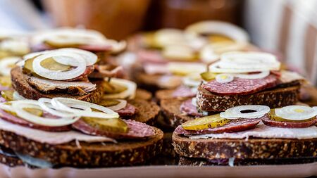 Bread with meat, sausage and onions on a tray in an outdoor cafe. Quick snacks., selective focus -...