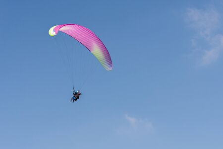 Geneva, Switzerland - April 14, 2019: Paragliding in Swiss Alps over the mountains against clear...
