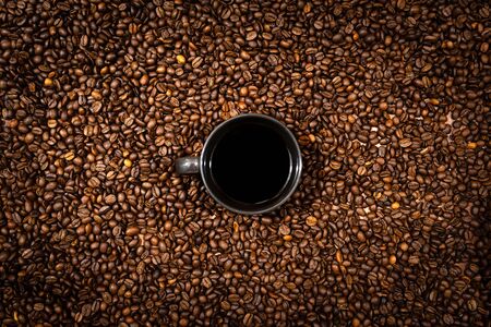 Top view of black coffee mug on the coffee beans background - imageの写真素材