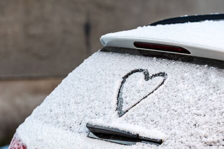 Heart shape on snow covered car rear window, close-upの写真素材