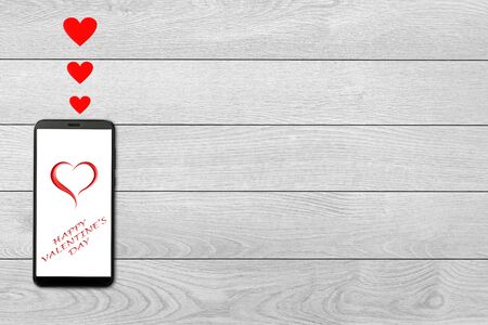 Valentine day concept, love message - hearts flying out smartphone, isolated on white wooden...