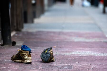 New York, USA - June 23, 2019: on the street abandoned old dirty sports shoes