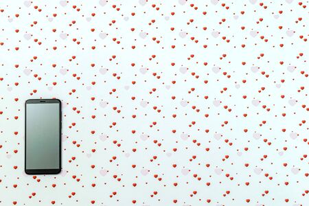Smartphone with blank screen on a white bacground with colorful hearts shapes. Concept of Valentines...