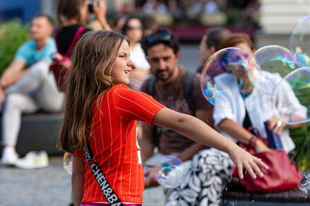 Old Town Square, Riga, Latvia - August 16, 2019: Children playing with colorful soap bubbles floating in the foregroundのeditorial素材