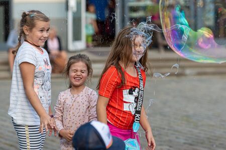 Old Town Square, Riga, Latvia - August 16, 2019: Children playing with colorful soap bubbles floating in the foregroundのeditorial素材