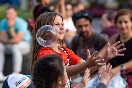 Old Town Square, Riga, Latvia - August 16, 2019: Children playing with colorful soap bubbles...