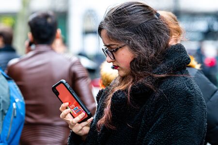 London, England, UK - January 2, 2020: Young woman with glasses standing in crowd of people staring...