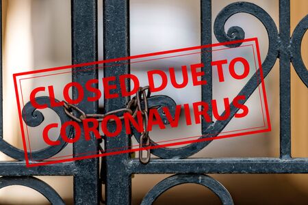 Closed Due To Coronavirus - sign on the background of an ornamental iron gate locked with chainの写真素材