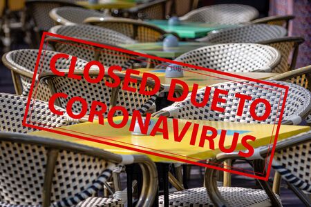 Closed Due To Coronavirus - sign on the background of an  empty cafeteria or restaurant tables with chairs on streetの写真素材