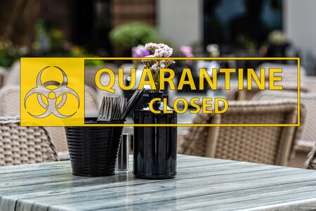 Coronavirus quarantine sign on the background of an empty wicker chairs and colorful tables in the outdoor cafeの写真素材
