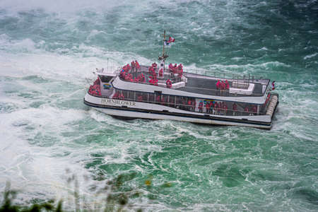 Niagara Falls, NY, USA - June 13, 2019: Ship with tourists moves to Niagara falls, Falls boat tour...
