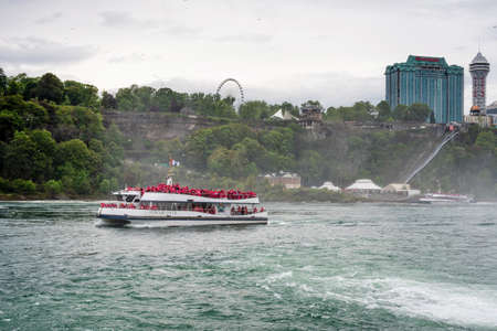 Niagara Falls, NY, USA - June 13, 2019: Ship with tourists moves to Niagara falls, Falls boat tour experience is North America oldest attraction, and has drawn millions of visitors since 1846のeditorial素材