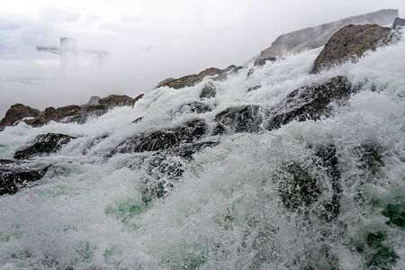 Niagara Falls splash close-up on a sunny day, a background of water flowing over the stonesの写真素材