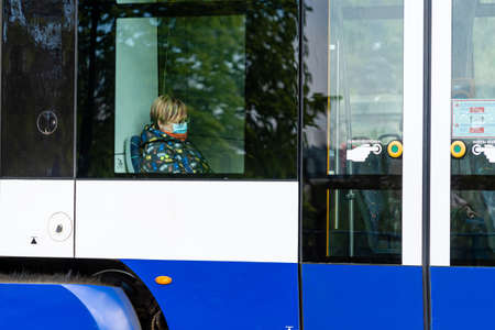 Riga, Latvia - May 14, 2020: woman is seen through the window of a public tram wearing a face mask...