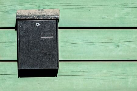 green mail box on the traditional light green wooden wall of houseの写真素材