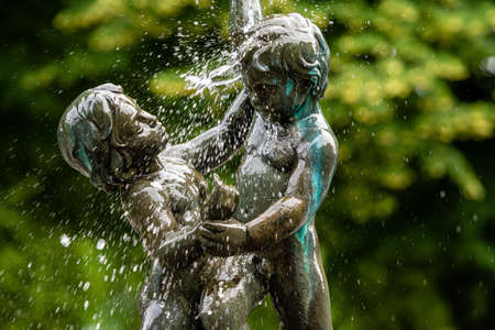 Riga, Latvia- July 3, 2020: fragment of the oldest Riga fountain SEASONS in Vermane Garden, sculptures of two boys in splashes of water on a defocused backgroundのeditorial素材