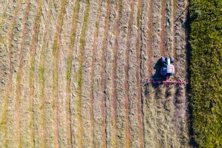 Top view of tractor with tedders, drying mowed hayの写真素材