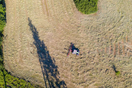 Top view of tractor with tedders, drying mowed hayの写真素材
