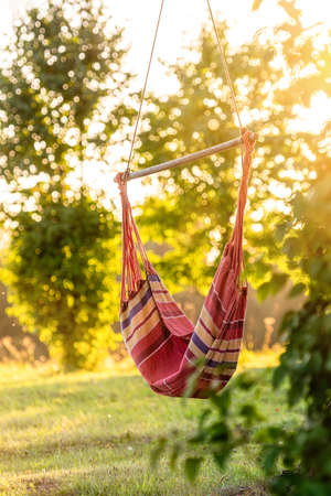 empty hammock in the garden by the tree in sunset lights, rest outdoor concept