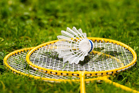 white shuttlecock on yellow badminton rackets in the green meadowの写真素材