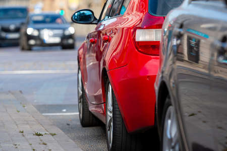 rows of different cars parked along the roadside in crowded cityの写真素材