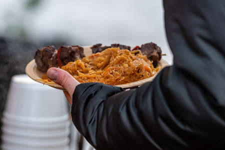 stewed cabbage with sausages - a traditional dish at the annual Christmas market, hands holding a...