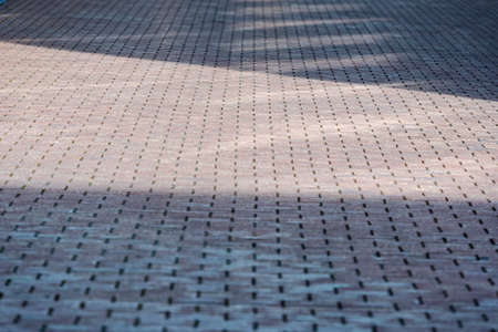 perspective view monotone gray brick stone pavement with shadow from buildings, texture background...