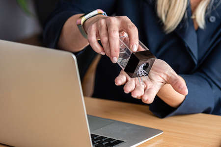 an office worker pours a paper clip from a container into his hand, close-up