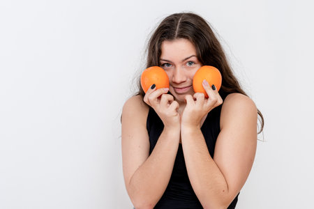 charming young attractive girl with orange fruits in hands, isolated on white background
