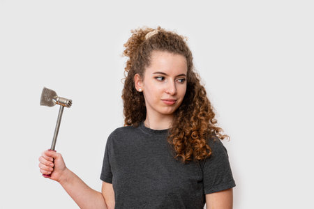 young woman with brown curly hair with an ax in her hands, isolated on a white backgroundの写真素材