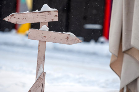 snowy wooden signpost with two nlank arrows on a colorful blurry backgroundの写真素材