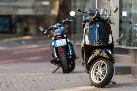 Riga, Latvia - October 7, 2020: Vespa scooter and motorcycle parked on the pavement of the old town