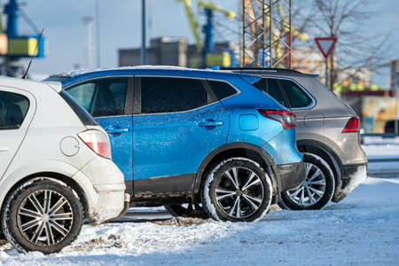 row of different cars parked  in the outdoor parking lot on a snowy winter day