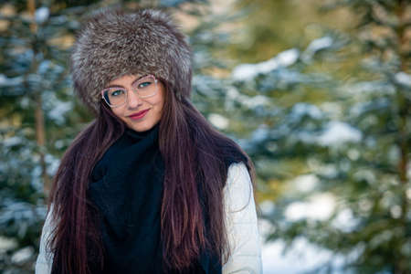 portrait of a woman in eyeglasses and white clothes in a cold winter forest