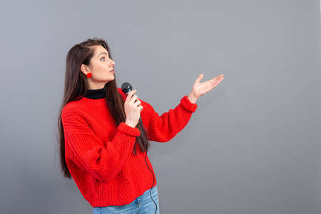 female conference speaker dressed in a red sweater during presentation calling for attention, isolated on greyの写真素材