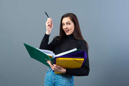 fashionable woman holding a colorfuls folders with documents, isolated on dark backgroundの写真素材